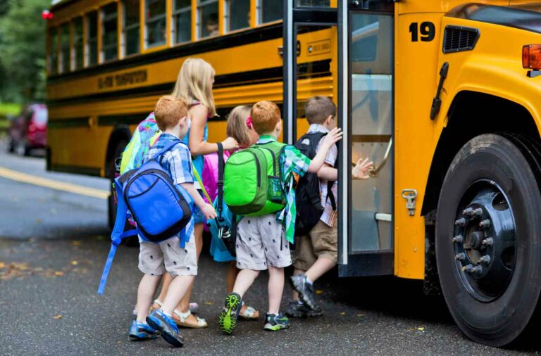 group of small kids with backpacks lined up outside a school bus. Feature image for an article on 4 Ways to Save Your Sanity In a New School Year