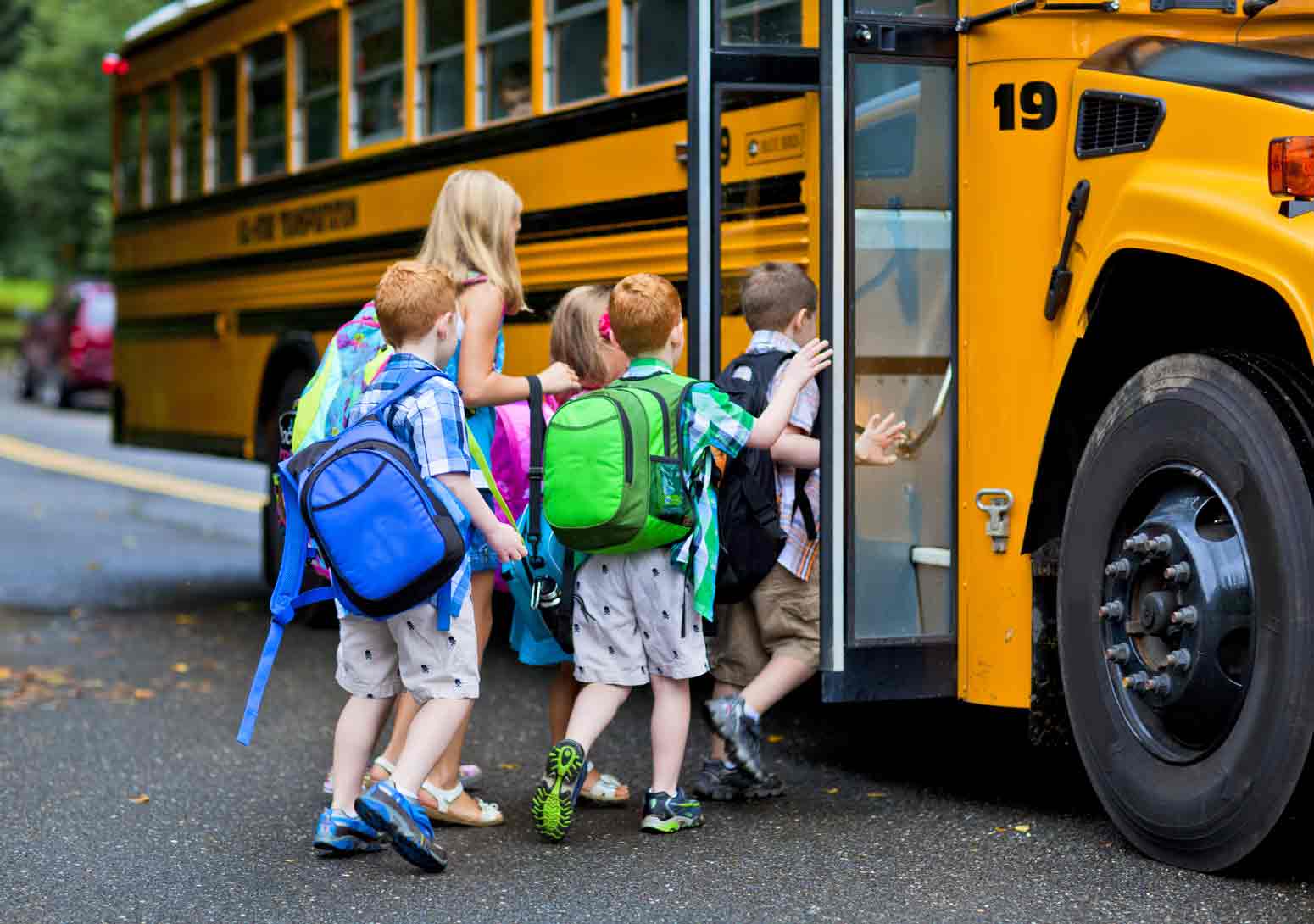group of small kids with backpacks lined up outside a school bus. Feature image for an article on 4 Ways to Save Your Sanity In a New School Year