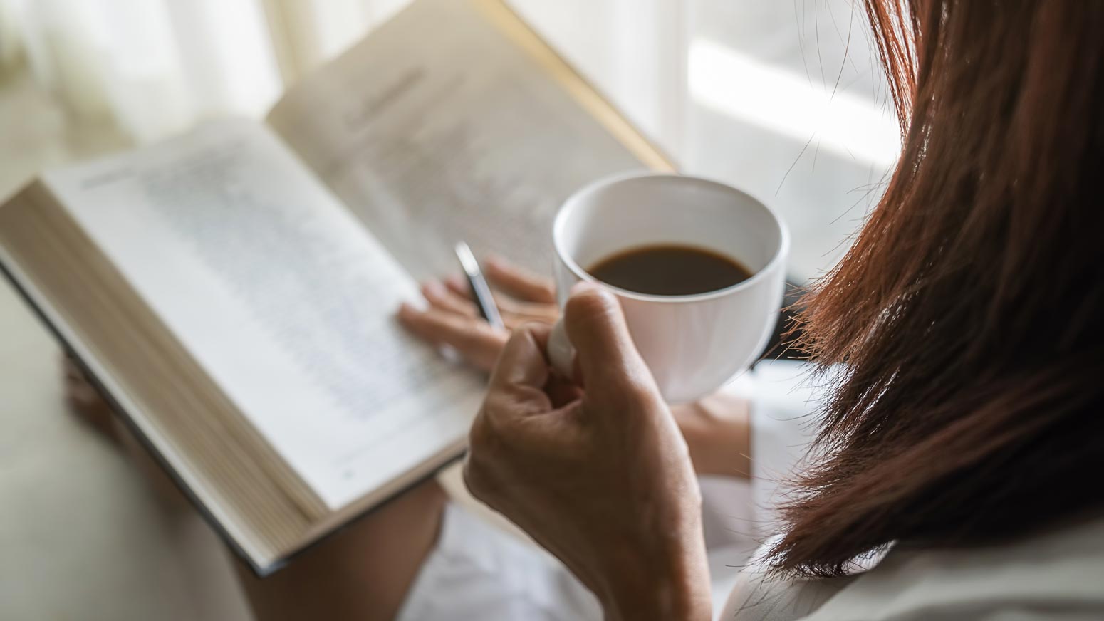 woman holding a cup of coffee with a Bible in her lap as part of her morning routine that feels doable