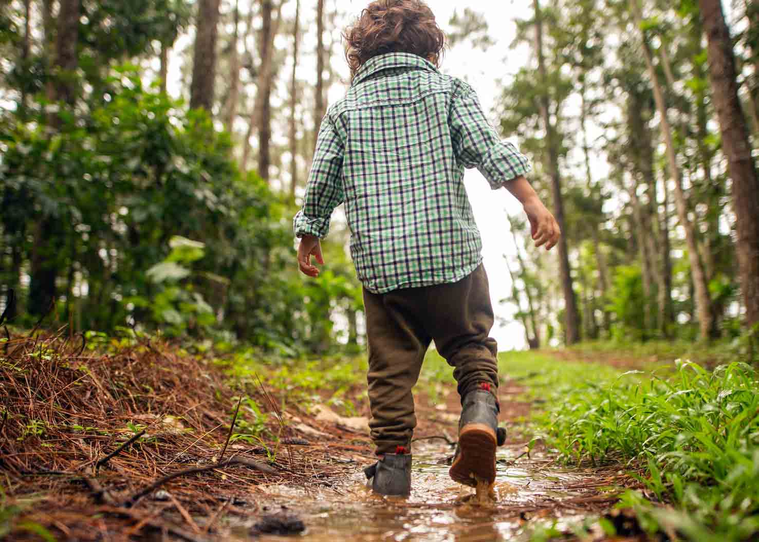 little boy walking through a mud puddle