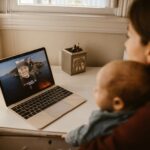 mom and baby talking to dad via facetime on a laptop. Feature image for 5 Ways to Stay Connected When a Family Member Is Traveling