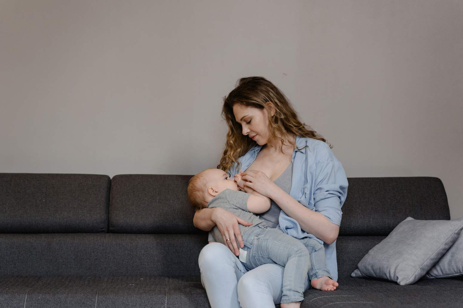woman sitting on couch breastfeeding her baby