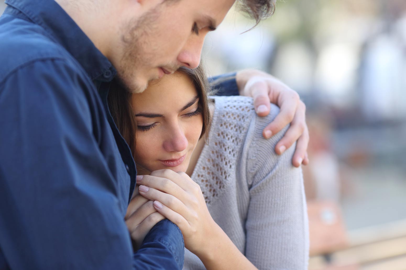 man with arm around woman, both with crestfallen faces