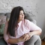 woman sitting on couch looking hopefully out the window ready with steps to move on