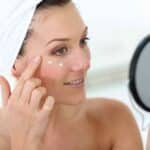 woman dabbing lotion on her face after a shower as one of the recommended skincare hacks for women