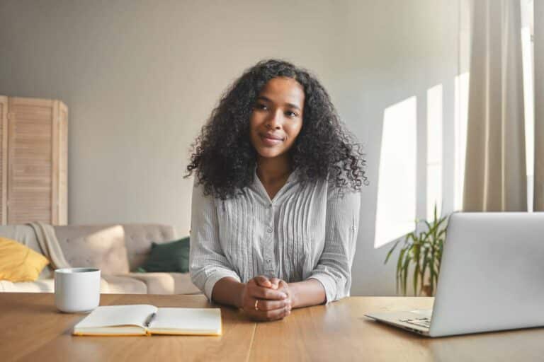 middle-aged woman smirking at her desk next to her laptop after learning to embrace the beauty of rejection