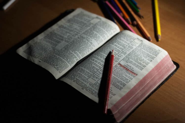 a Bible on a desk surrounded by colored pencils