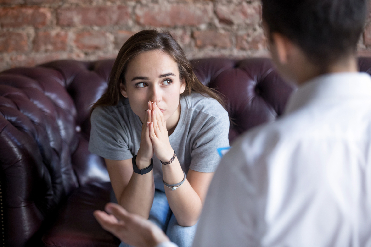 woman with hands clasped to her face in a therapist's office as an act of self-care when you've been cheated on