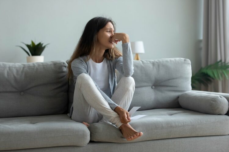 woman sitting on couch crying and looking out the window, wondering how to read the Bible when sorrow overwhelms you