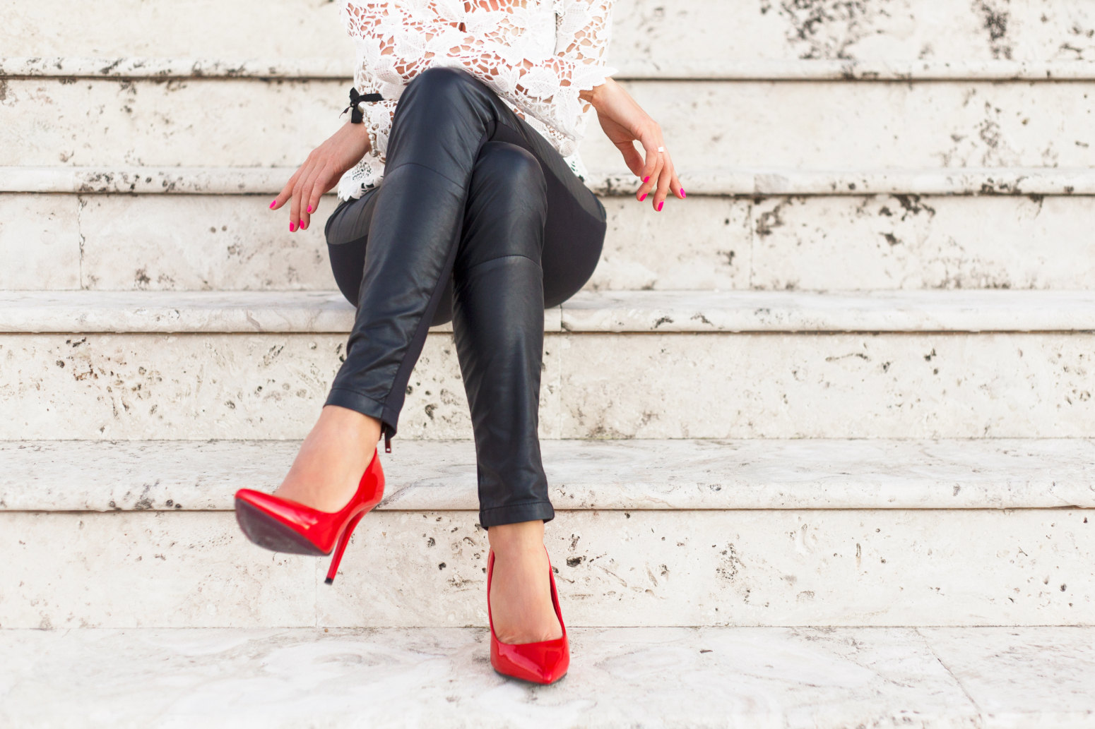 woman with leather pants and red heels sitting crossed-legged and confident on stairs because she learned how to say good riddance to shame