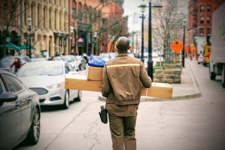 a mailman walking down a city sidewalk holding packages and the secret to a wonderful life