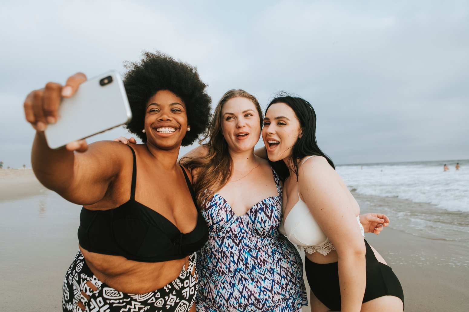 three happy women in bathing suits taking a selfie on the beach and not worried about body image issues