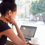 young woman on her laptop at a coffee shop checking off the top things to do when searching for your dream job