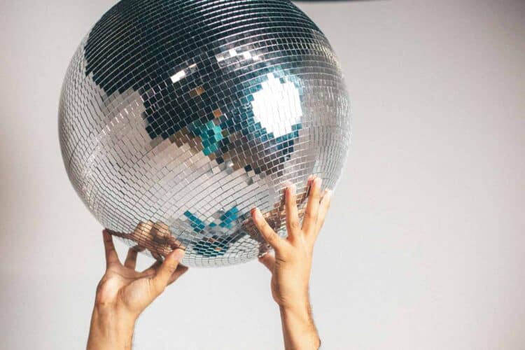 two hands holding up a large disco ball