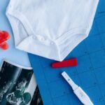 flat lay of a baby onesie, pregnancy test and other items that indicate you're ready to be a mom