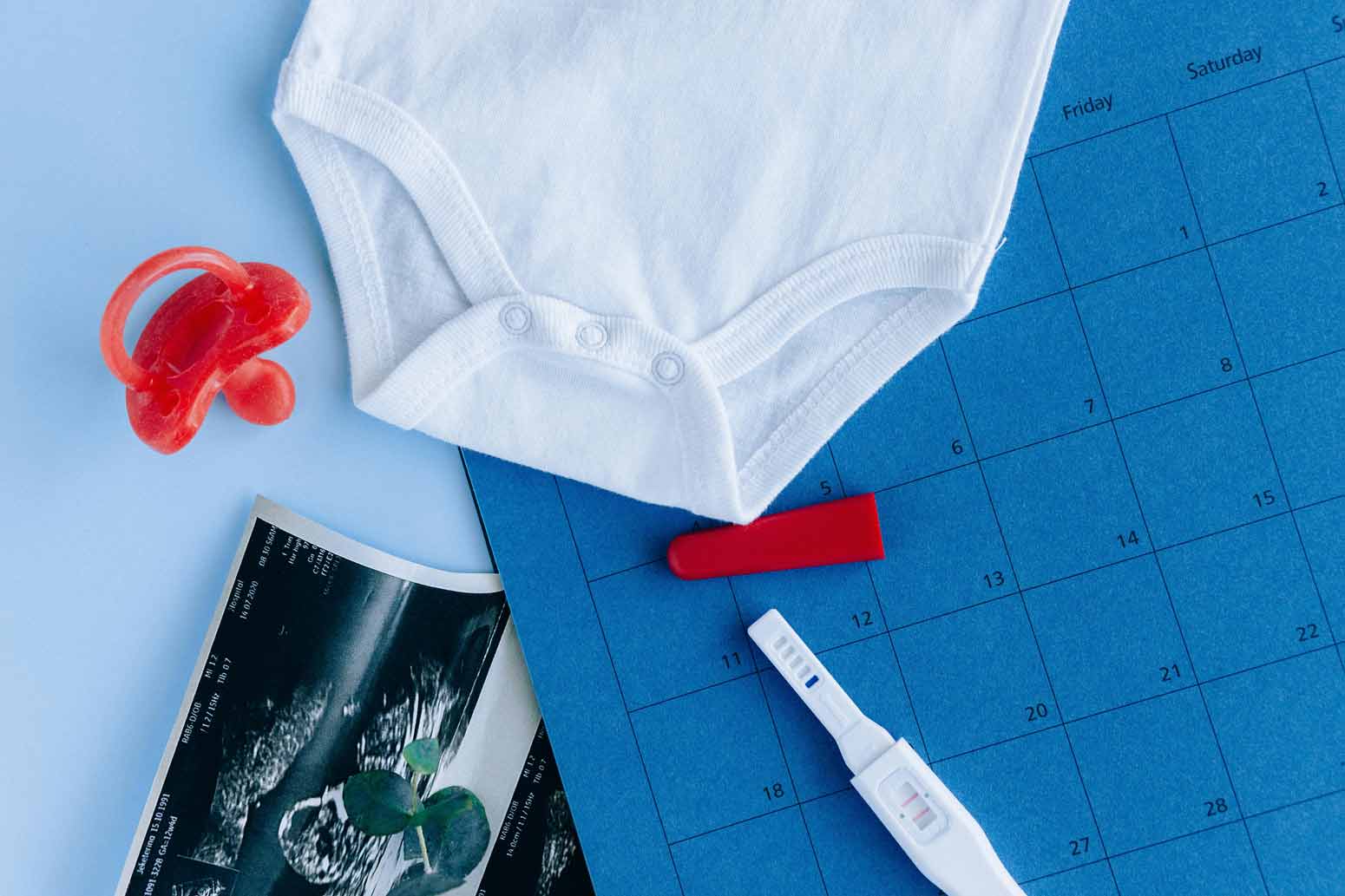 flat lay of a baby onesie, pregnancy test and other items that indicate you're ready to be a mom