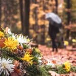 Woman with an umbrella walking away from a burial site wondering whether any good can come from her denied prayer