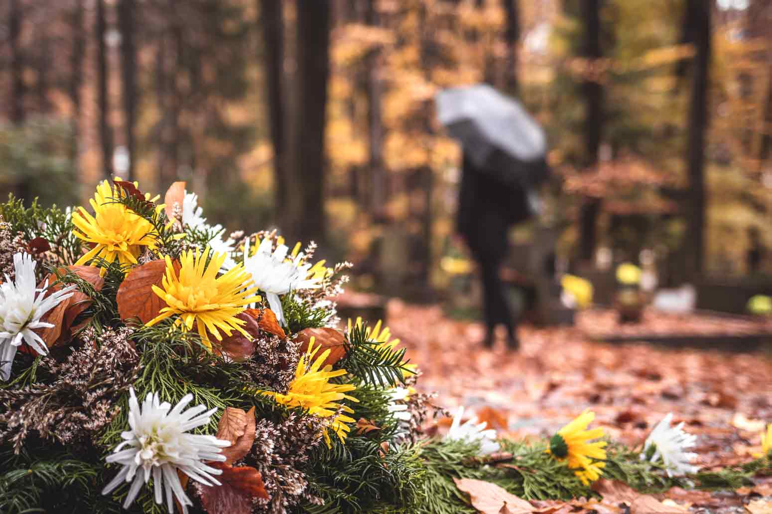 Woman with an umbrella walking away from a burial site wondering whether any good can come from her denied prayer