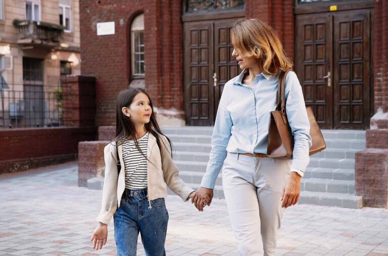 well-dressed woman walking in the street holding hands with her young perfectionist daughter