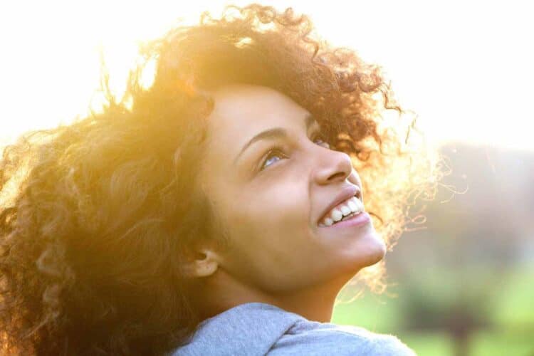 woman with curly brown hair smiling up at the sky because she learned the value in embracing your true identity