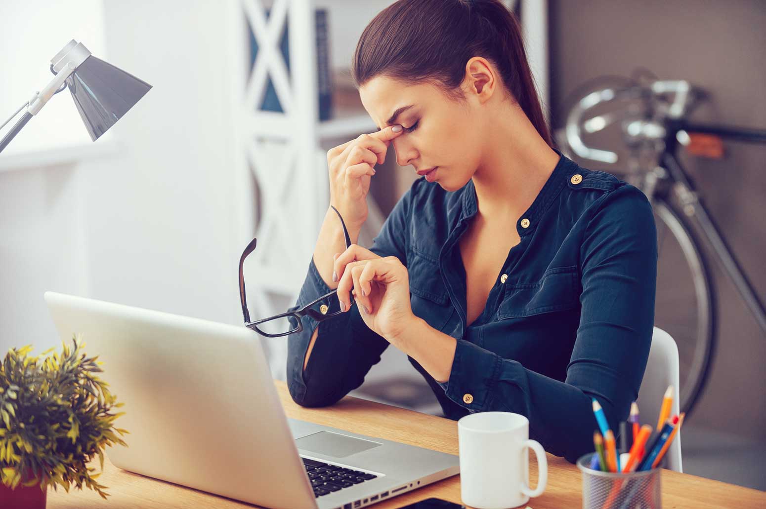 woman at a computer with her eyes closed and head in her hand wondering when to leave a job that's not serving her