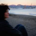 midde-aged brunette woman looking out over the ocean thinking about the message that God is writing your story