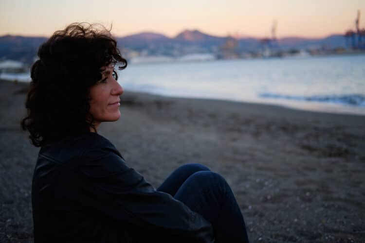 midde-aged brunette woman looking out over the ocean thinking about the message that God is writing your story