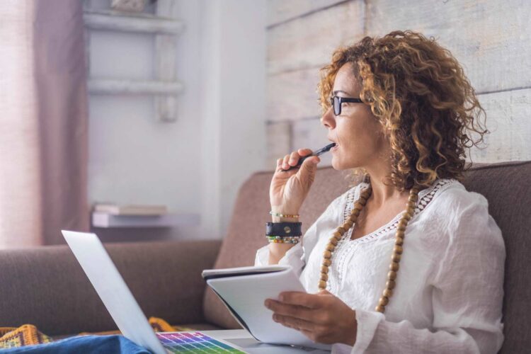 woman with a computer in her lap staring off and wondering how she can find rest amid the busyness of change