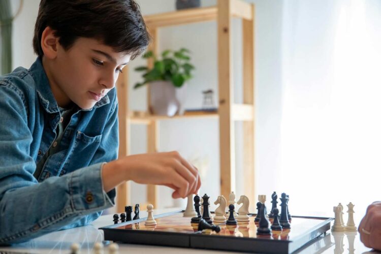 A young boy focused on a chess game, representing the importance of recognizing when to let your kids quit