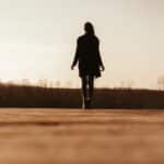 ground-level view of woman from behind walking on a road reflecting after a friend's death