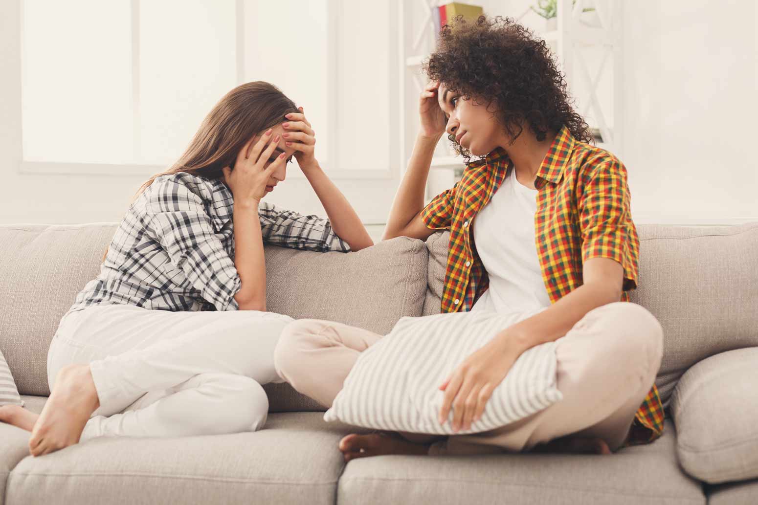 two women sitting on a couch in distress since one is leading an unhealthy life