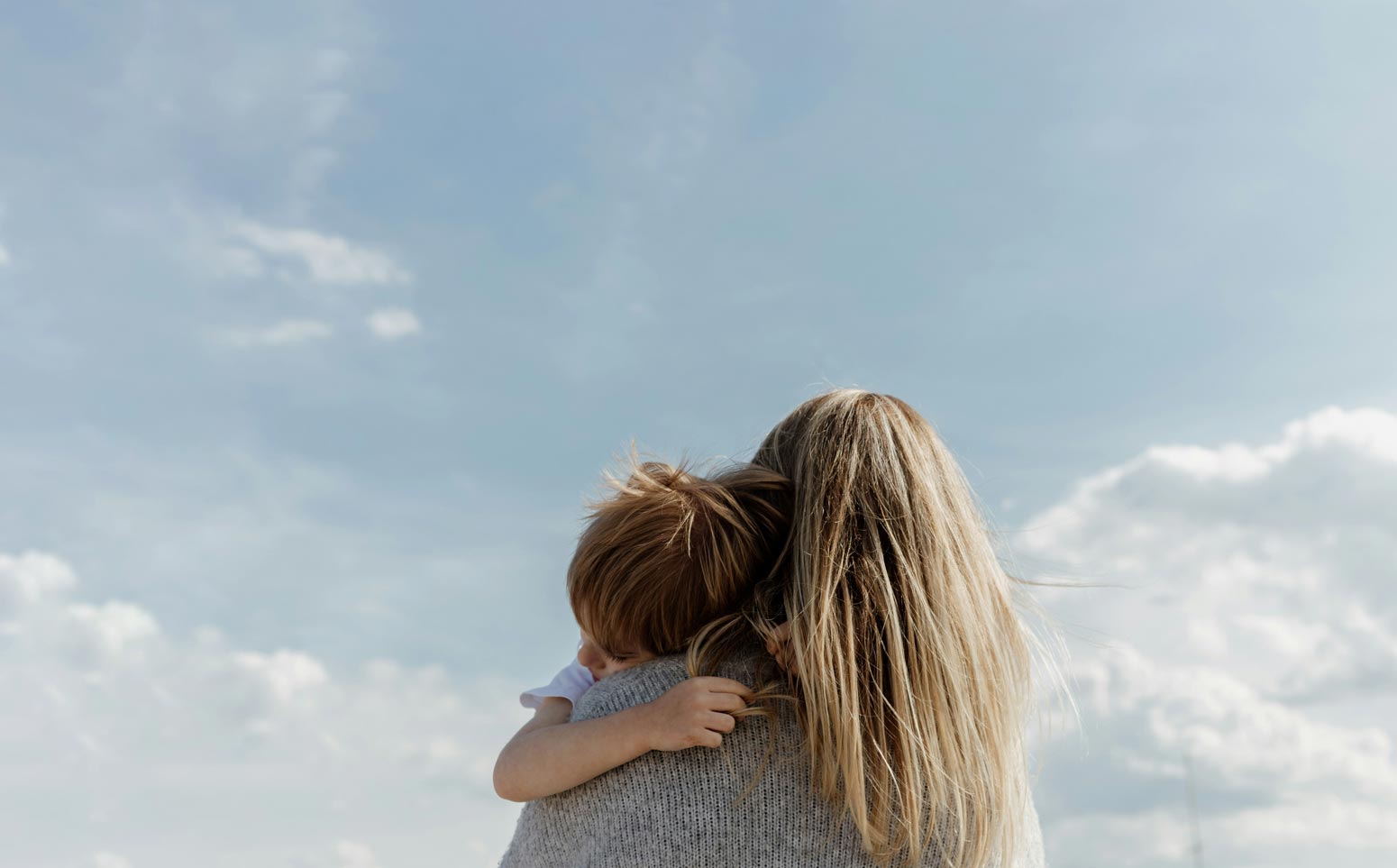 view from behind of mother holding a young boy and wondering "is motherhood my purpose?"