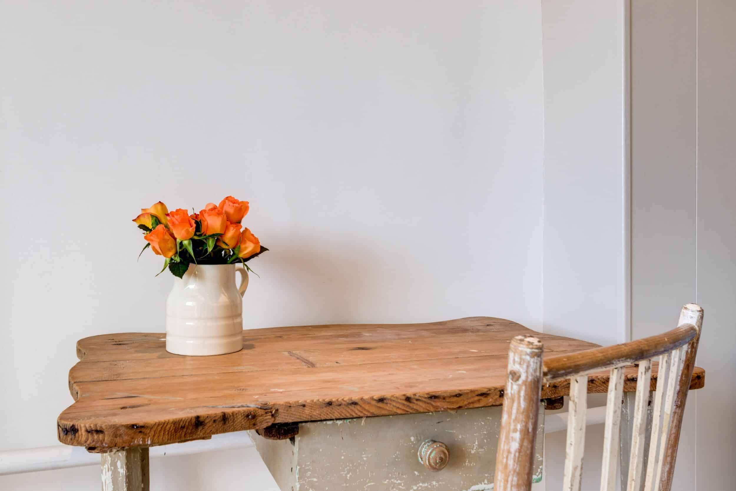 a simple wooden desk with a bouquet of flowers on top, symbolizing a home after you learn to simplify your life