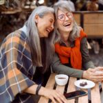 Two older women laughing over coffee, showing what can happen when you want more friends and take a chance on connection