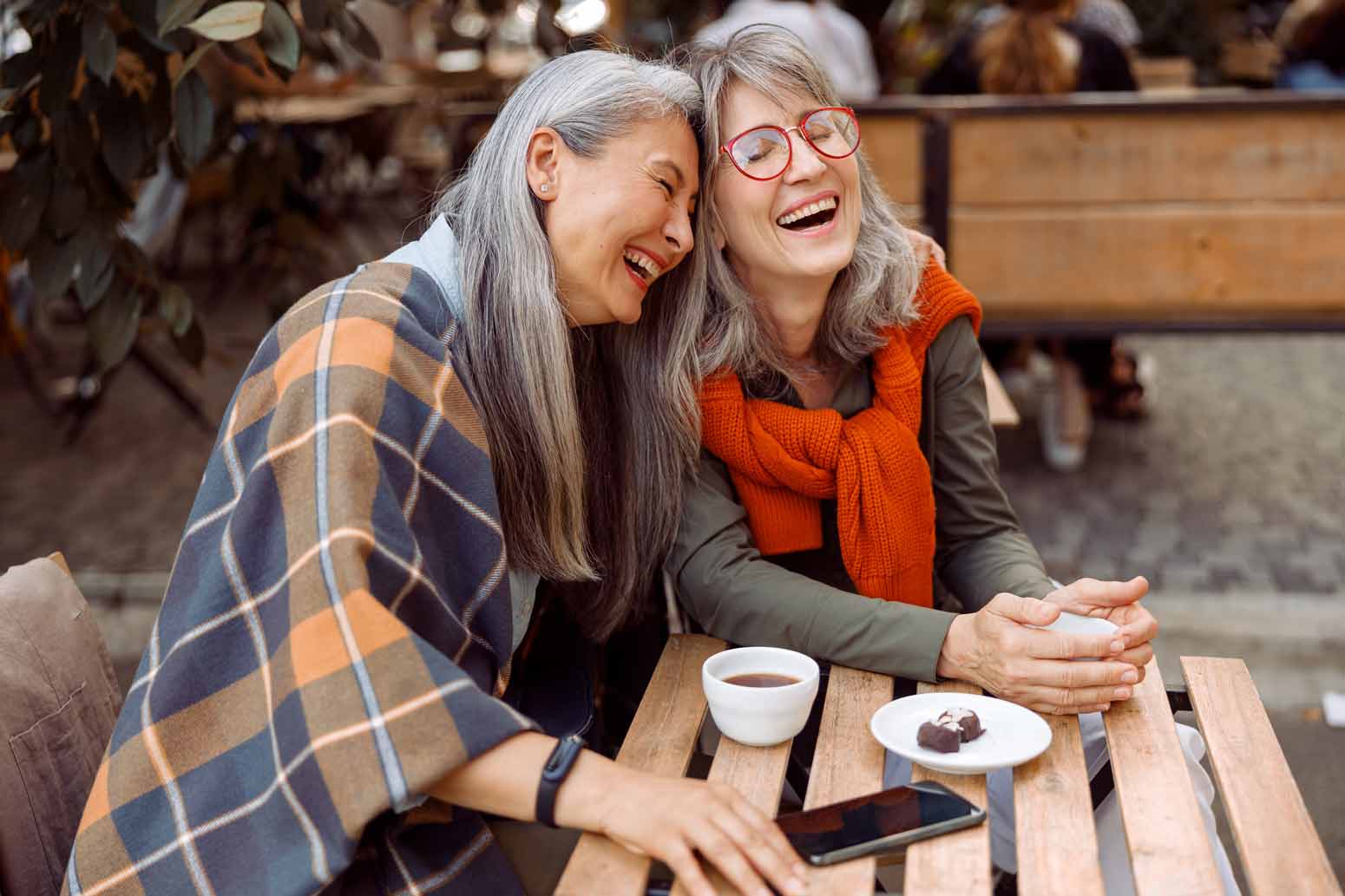 Two older women laughing over coffee, showing what can happen when you want more friends and take a chance on connection