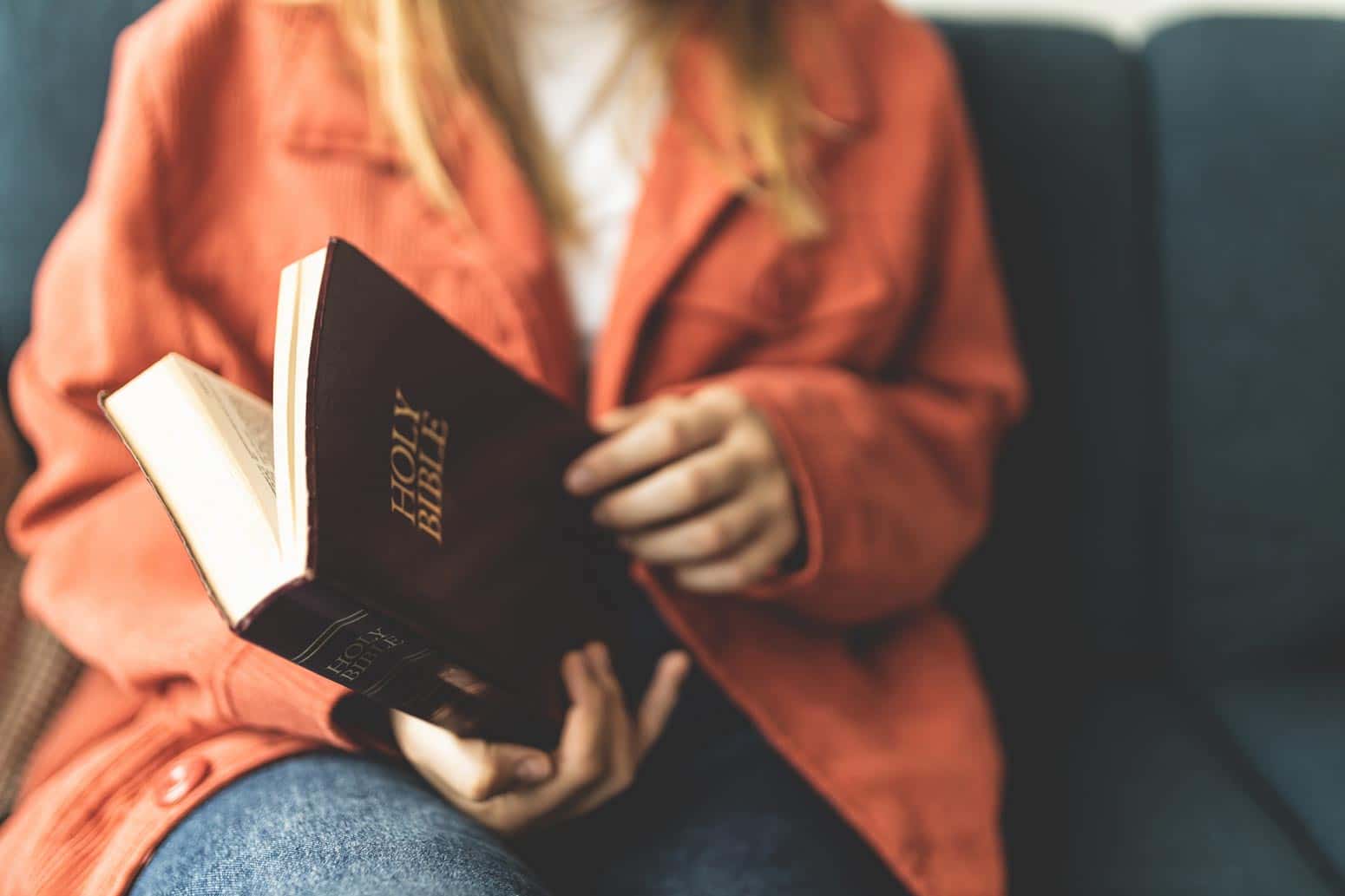 woman sitting down and thumbing through a Bible, one of a few morning practices to draw closer to Jesus