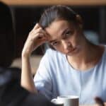 woman with a look of annoyance staring at a man sitting across from her