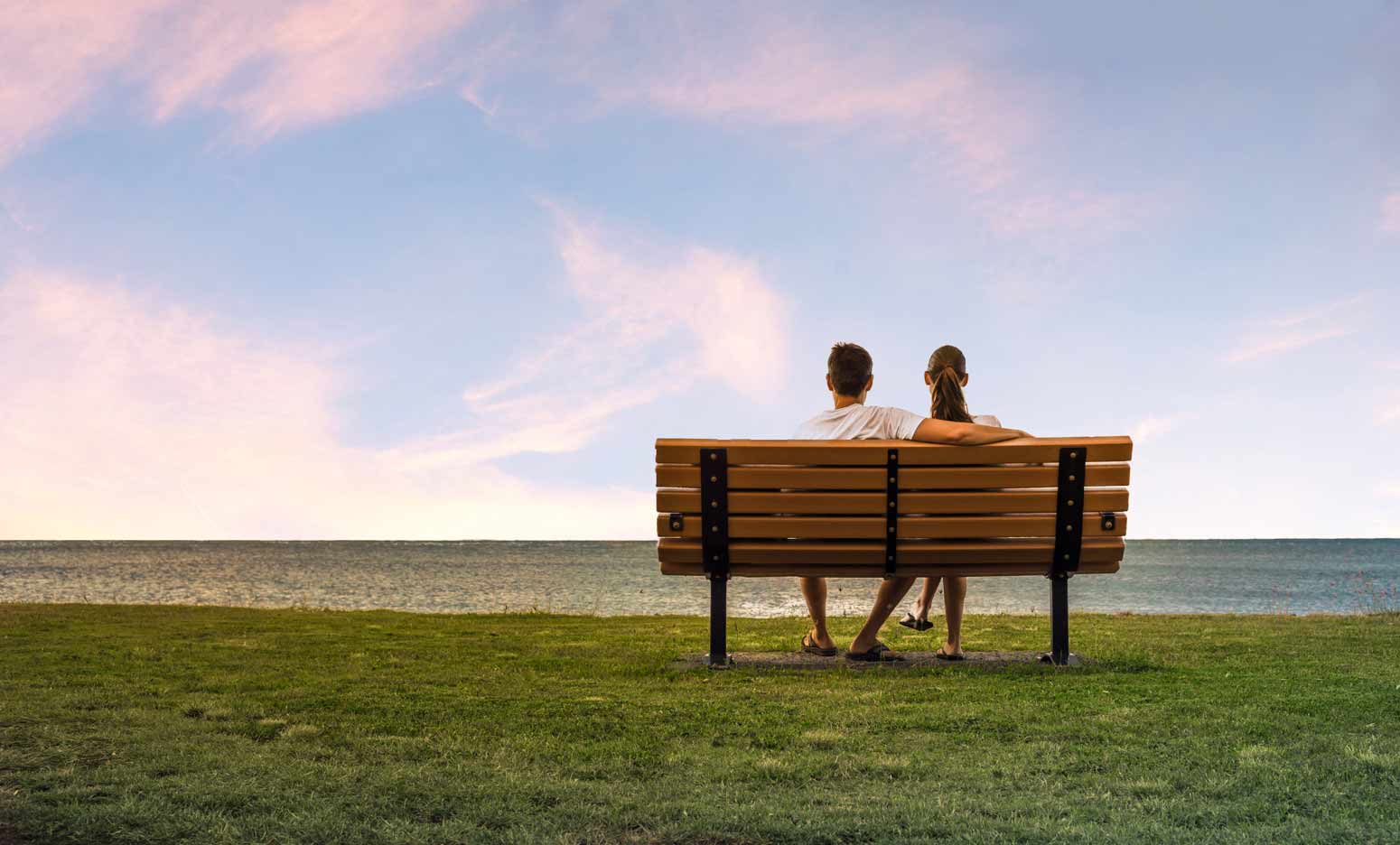 after pondering what steps to take when you start dating again, a couple sits together on a bench at sunset