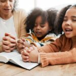 woman cultivates her young children's faith by praying over a Bible with them