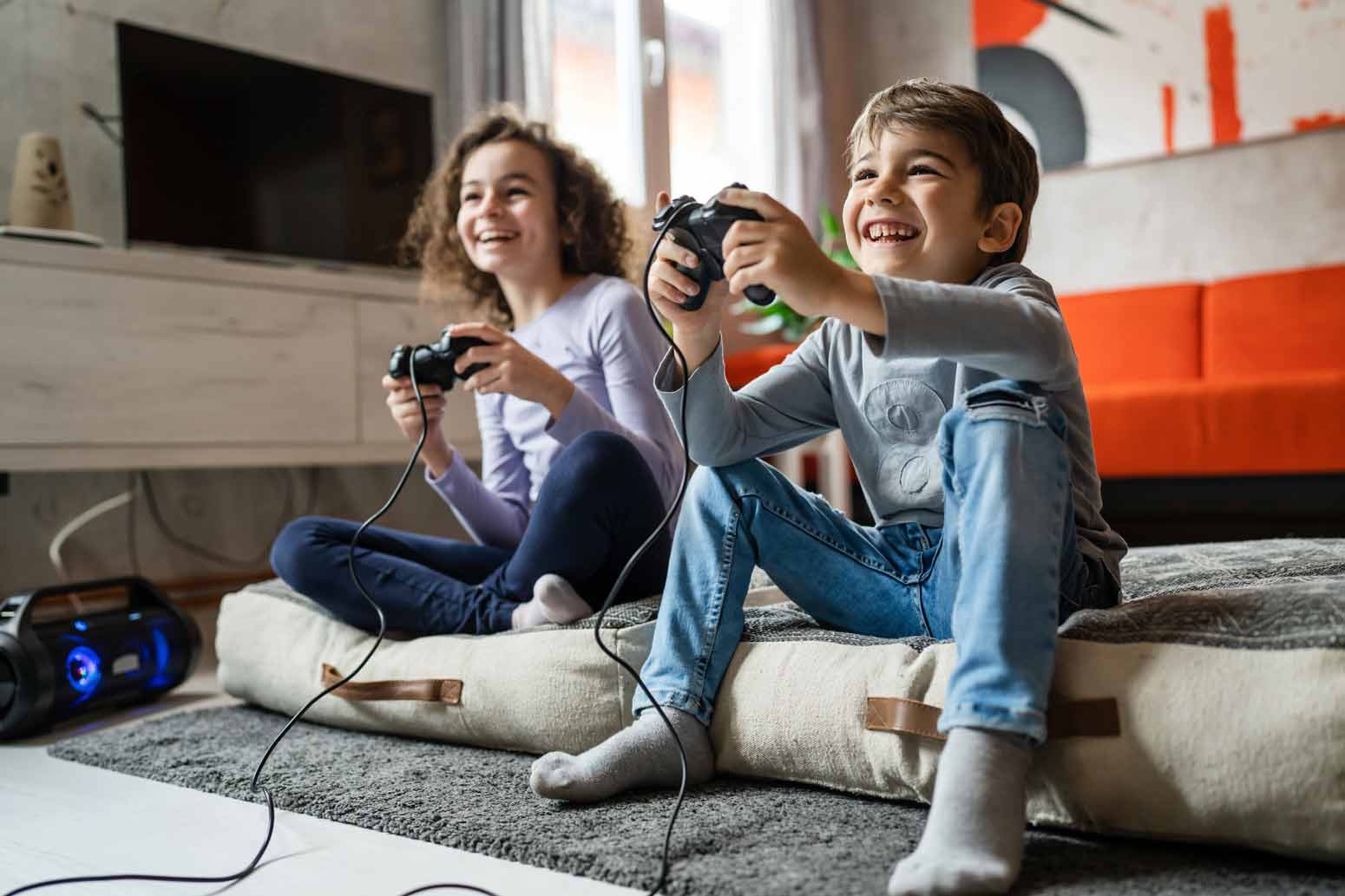 a young girl growing up with brothers plays video games on the floor with her brother