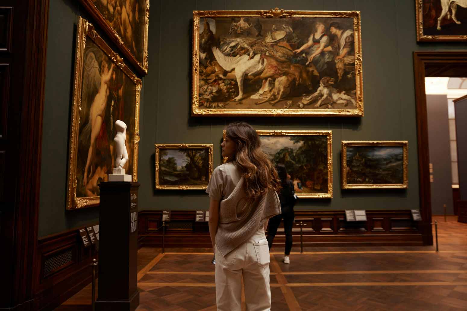 woman in a museum looking at masterpieces of art, even though she is one—a poiema