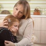 a woman comforting and embracing a young upset girl