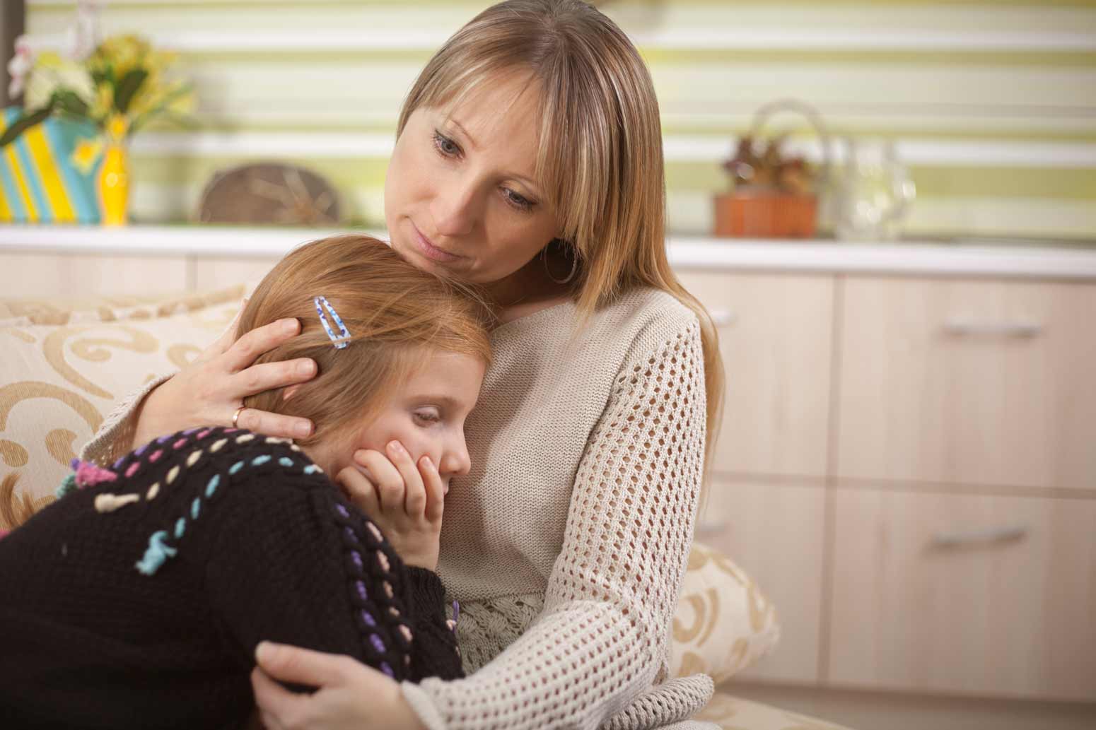 a woman comforting and embracing a young upset girl