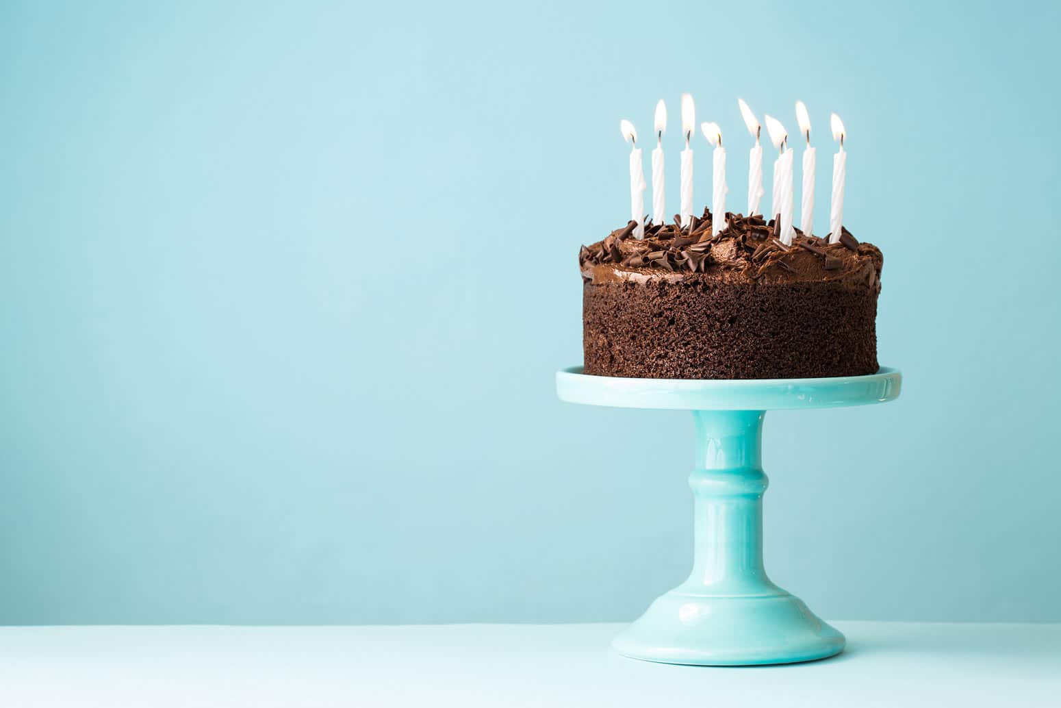 a chocolate cake with candles sitting on a blue pedestal, an example of many types of birthday freebies one can claim