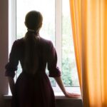 a silhouette of a woman staring out of a window, illustrating the search for filling the empty Space When Your Child Leaves Home