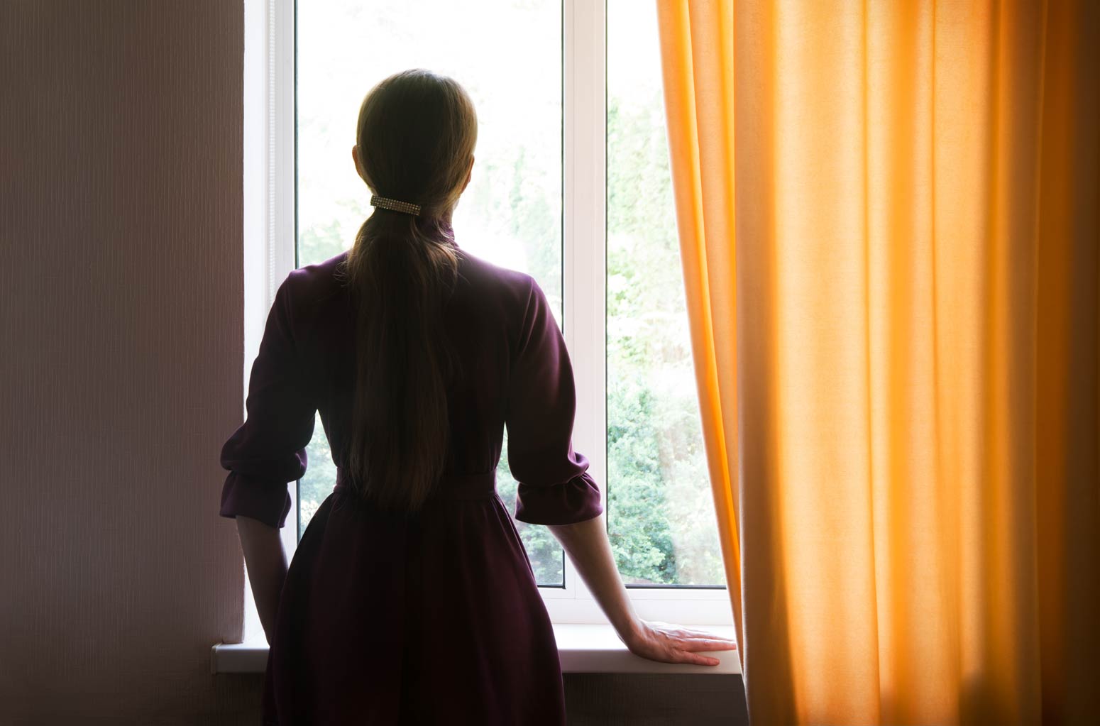 a silhouette of a woman staring out of a window, illustrating the search for filling the empty Space When Your Child Leaves Home