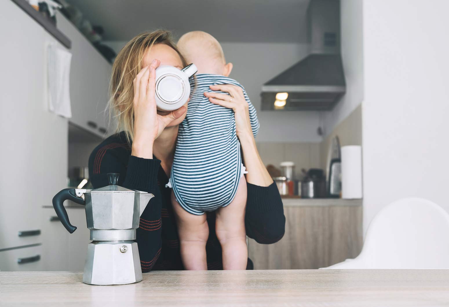 tired mom holding baby in one hand and drinking coffee in the other because it isn't selfish to take time for yourself