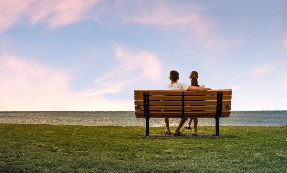 after pondering what steps to take when you start dating again, a couple sits together on a bench at sunset