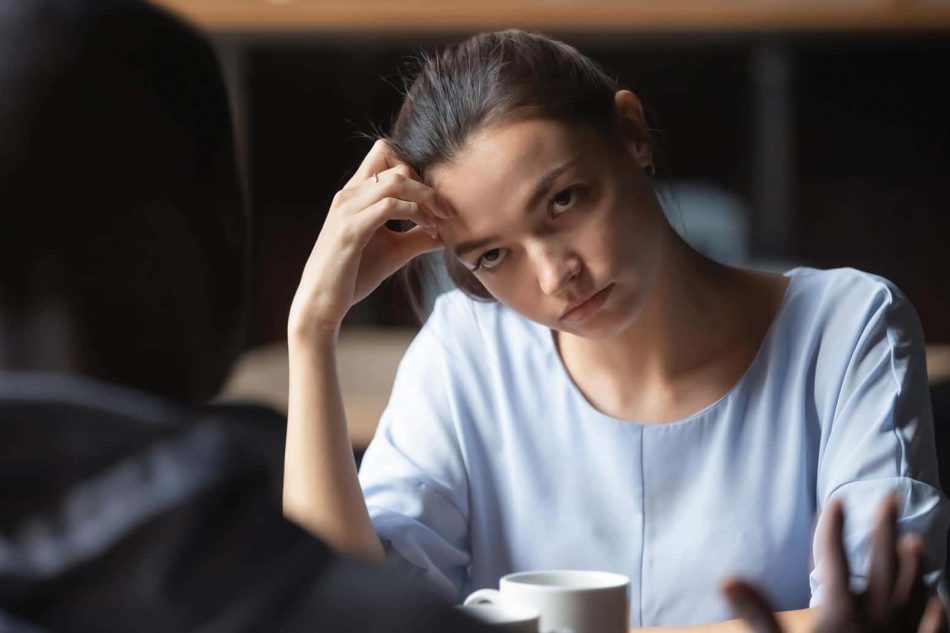 woman with a look of annoyance staring at a man sitting across from her